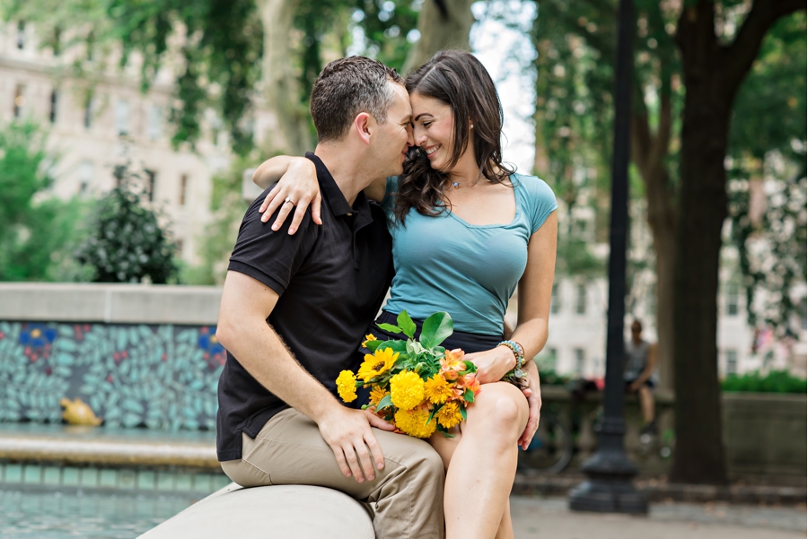 A woman sits on her fiance's lap at the fountain in Rittenhouse Square.